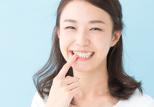 歯を指さして笑顔の女性