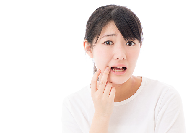 口を開けて歯を指さす女性
